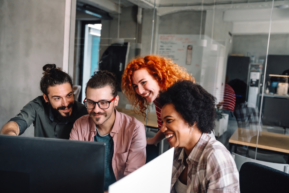 Software development team collaborating on computers to support an IBM Notes migration and modernize legacy systems.