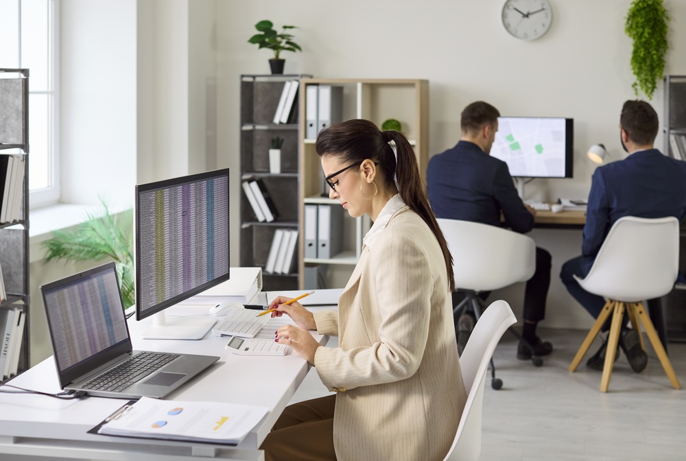Enterprise architect analyzing legacy system modernization data across multiple computer screens.